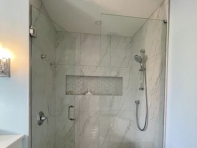 Curbless custom shower with linear drain and stainless drain grate, customer mitred niche